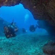 Two divers swimming through an underwater cave in Kauai, Hawaii, photographed during an excursion with Fathom Five Divers