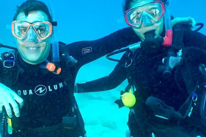 Two scuba divers smiling warmly at the camera, perfectly capturing the joy of underwater exploration in Kauai, Hawaii with Fathom Five Divers