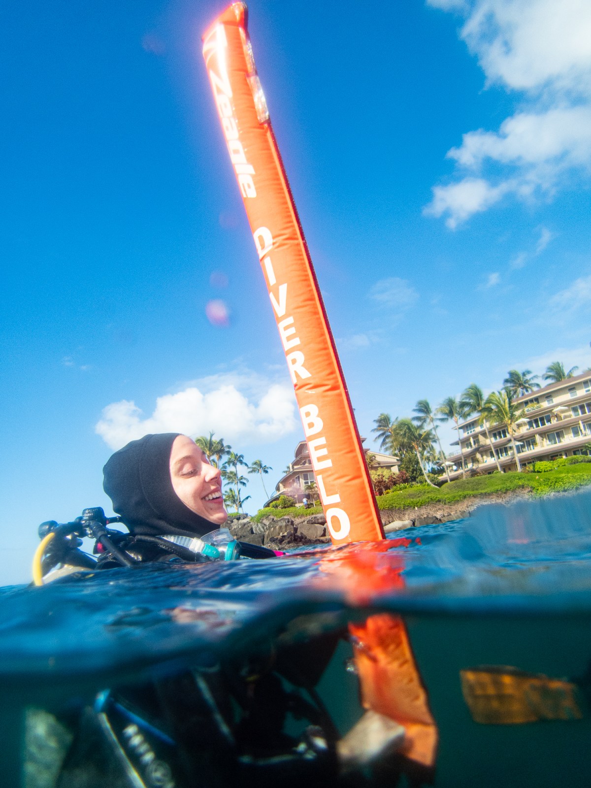 Reefwave Rendezvous: Nikon D850 Captures Playful Dance of Diver and Buoy Blonde dive instructor floating near an orange buoy at Koloa Landing, Kauai, Hawaii.