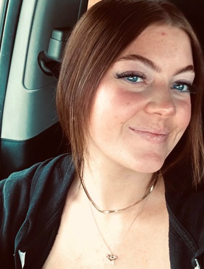 Screenshot a woman wearing glasses and smiling at the camera